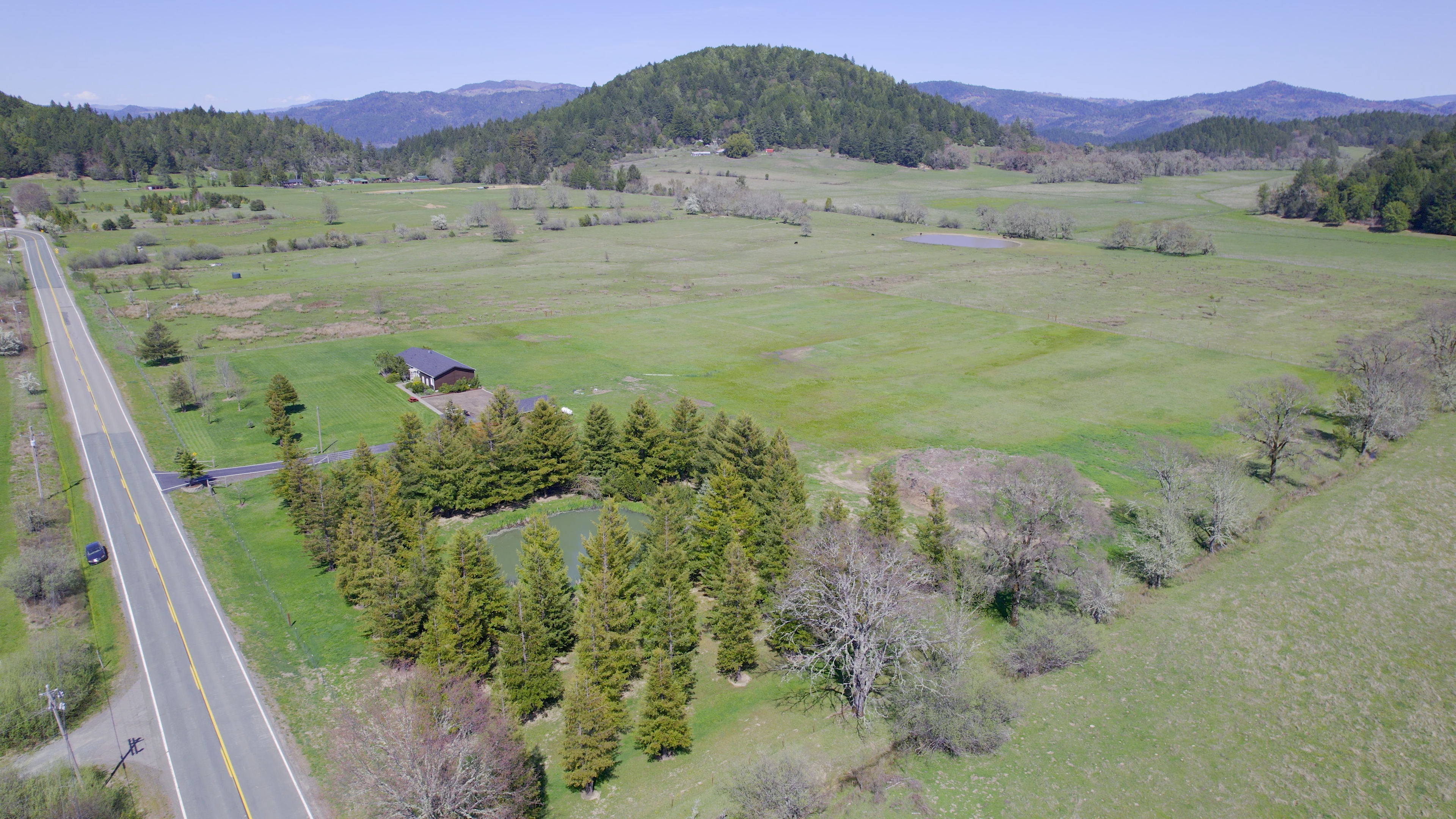 View of property, home, pond, land, trees, mountains