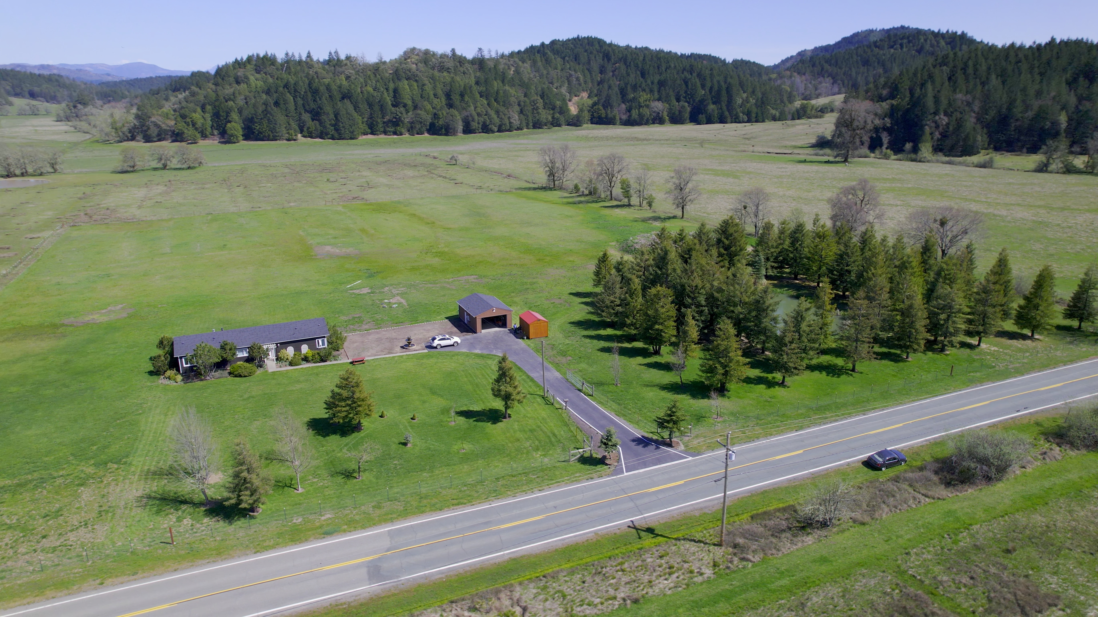 View of home, pond, trees, mountains in distance